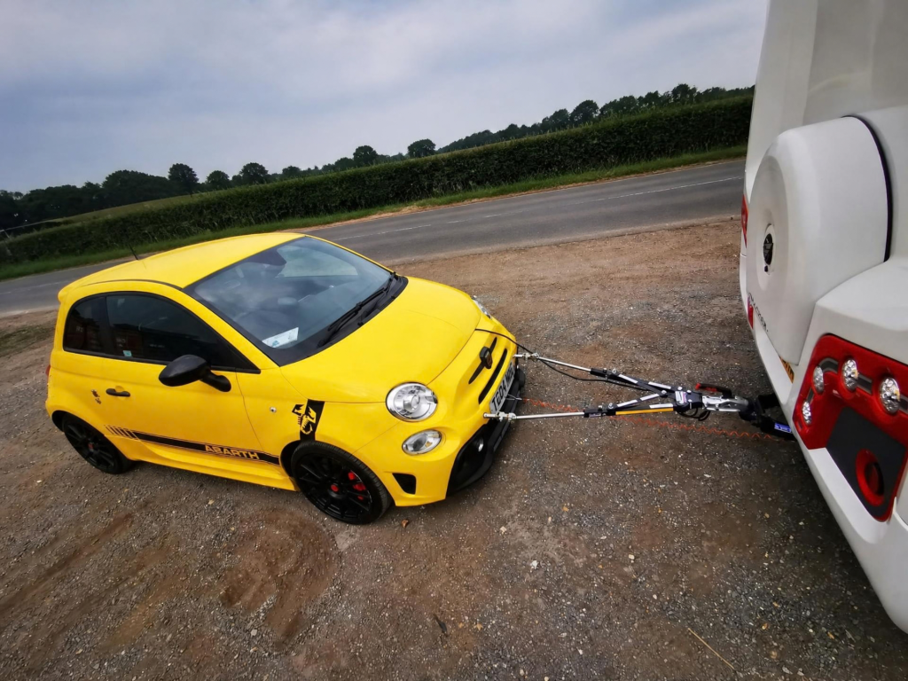 Close view of TowGlide A-frame connecting a yellow Abarth to a motorhome